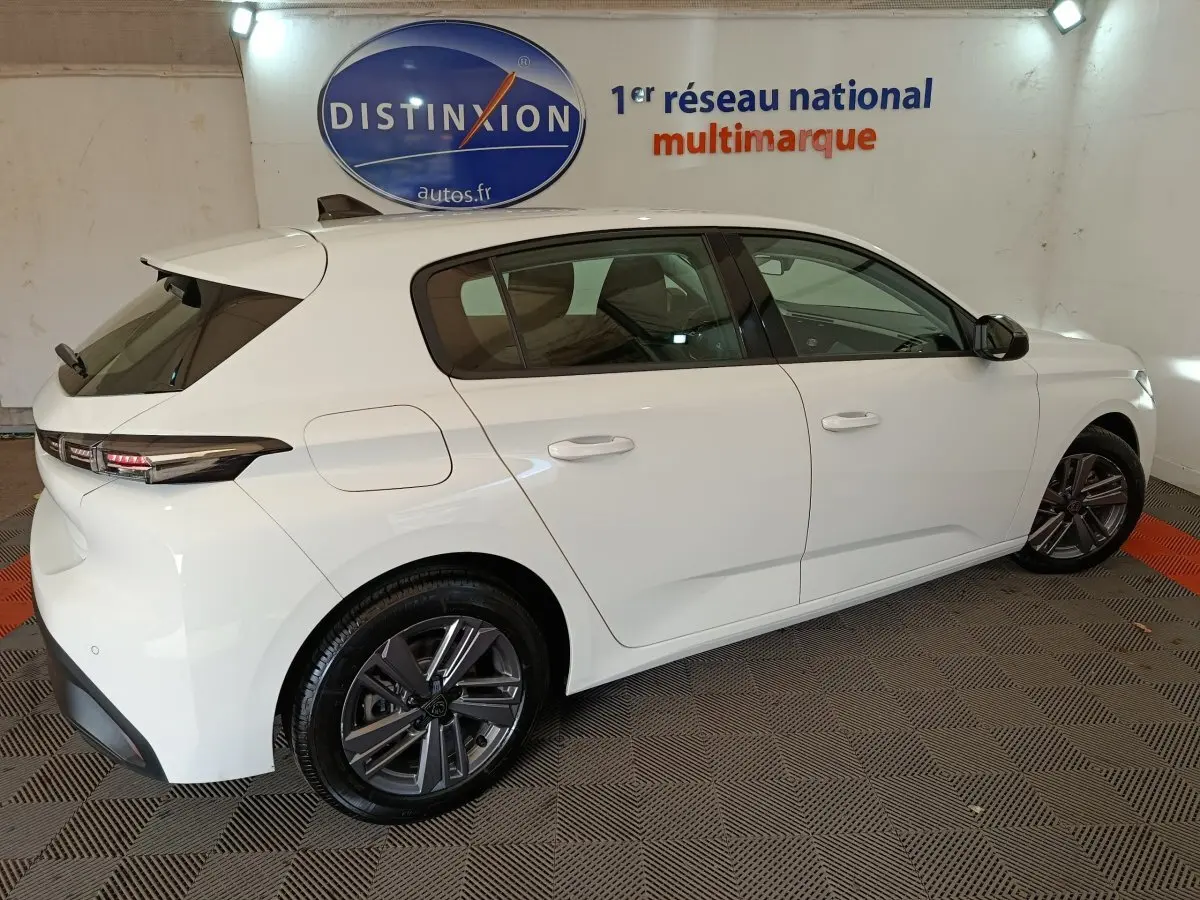 Peugeot 308 blanche vue de profil côté droit, avec jantes alliage et feux arrière LED distinctifs.