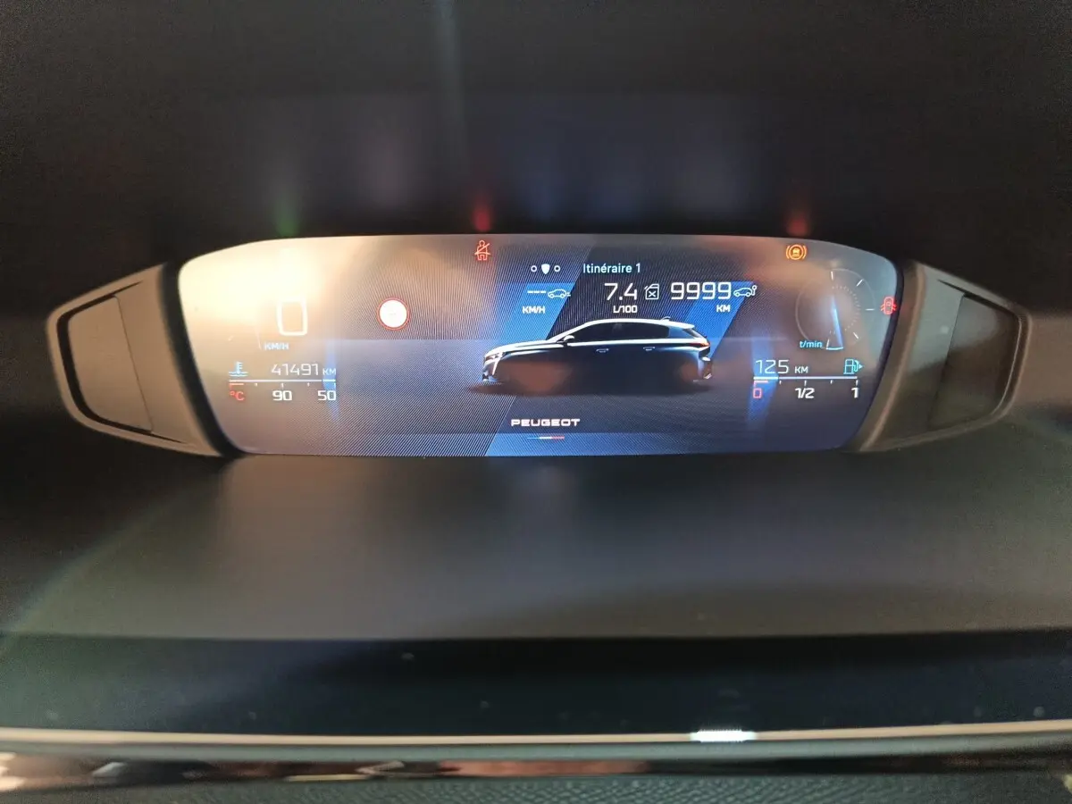 Affichage digital du tableau de bord de la Peugeot 308 blanc, montrant les informations de conduite et consommation.
