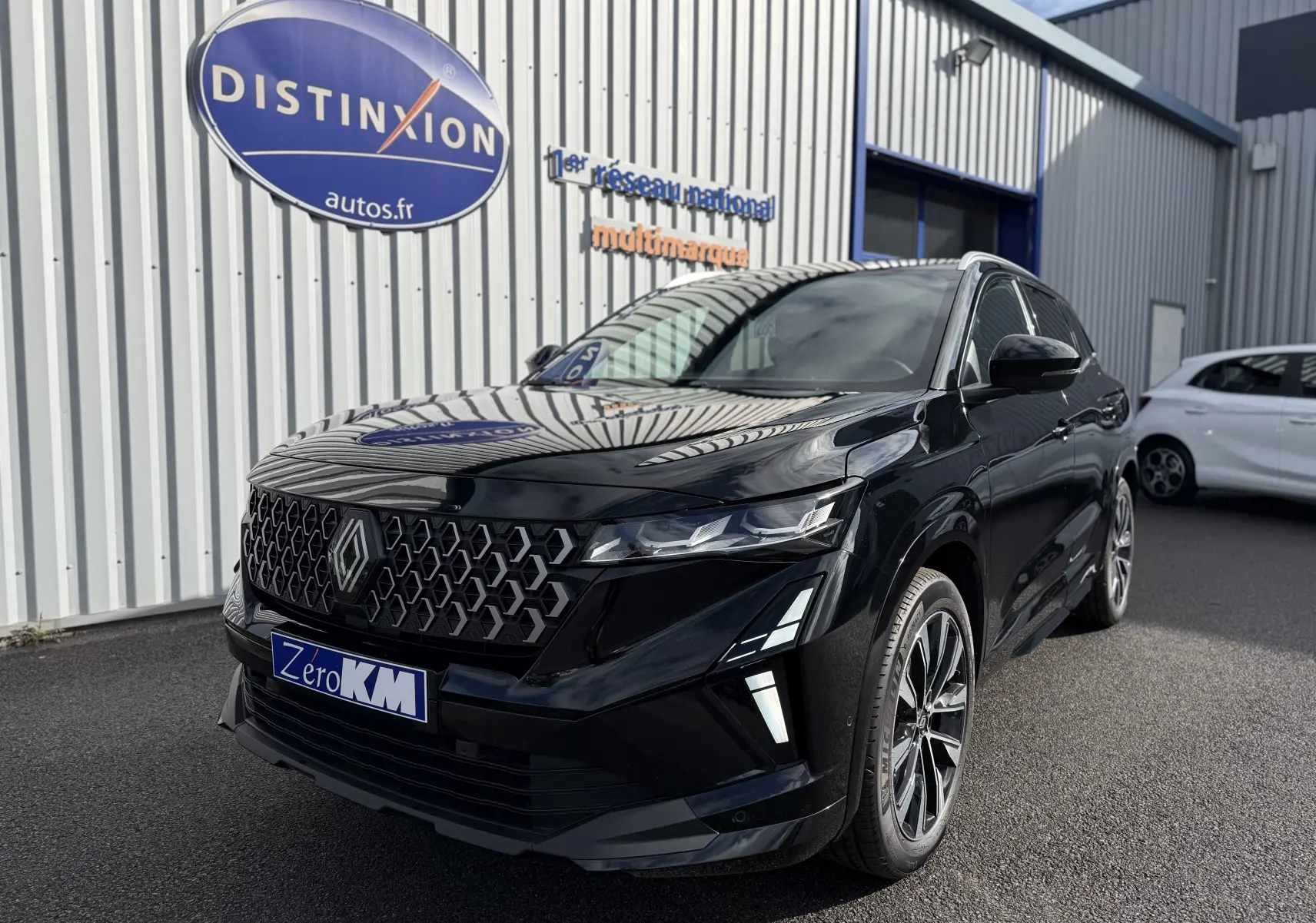 Renault Austral noir étoile en 3/4 avant droit, avec calandre hexagonale et feux LED distinctifs, stationné devant un bâtiment.