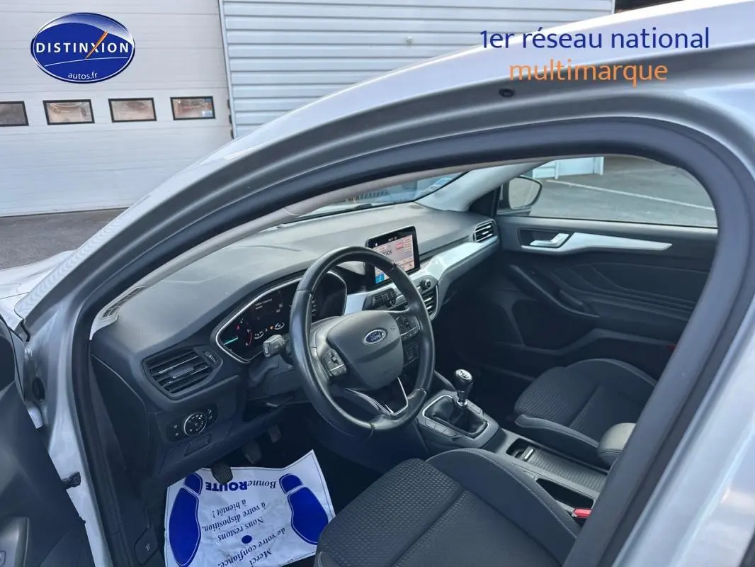Intérieur avant gauche d'une Ford Focus gris clair 2019, avec tableau de bord moderne et boîte manuelle visible.