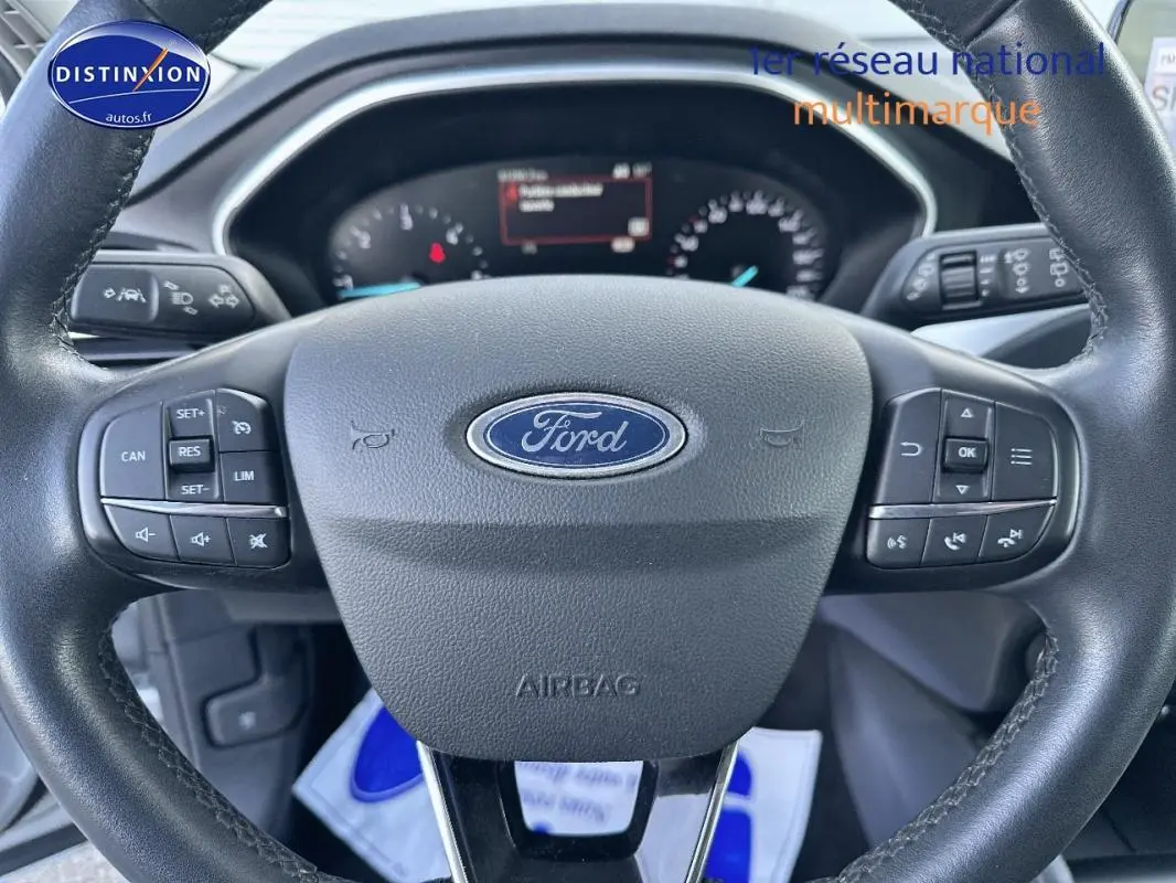 Gros plan sur le volant Ford d'une Focus 2019, montrant les commandes intégrées et le tableau de bord numérique.