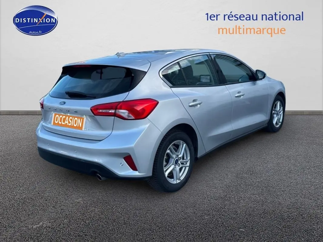 Vue 3/4 arrière droite d'une Ford Focus gris clair 2019 avec jantes alliage et feux arrière rouges distinctifs.