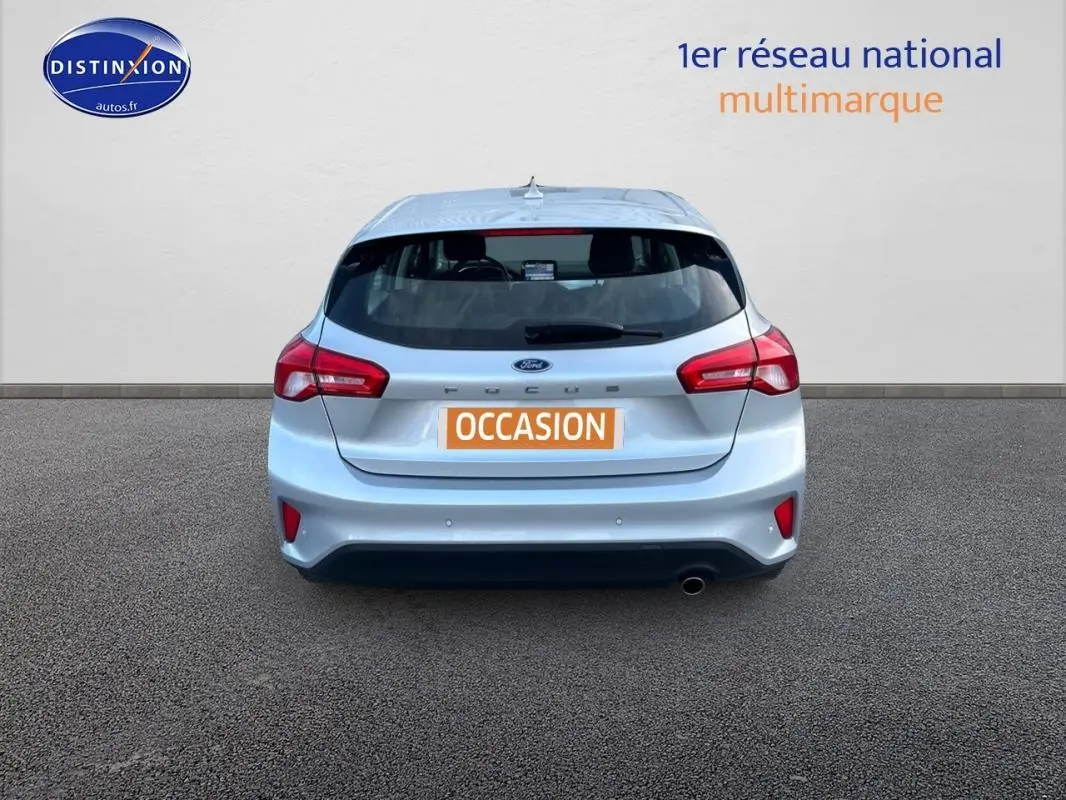 Vue arrière d'une Ford Focus gris clair 2019 avec feux rouges et plaque orange "OCCASION" sur fond neutre.