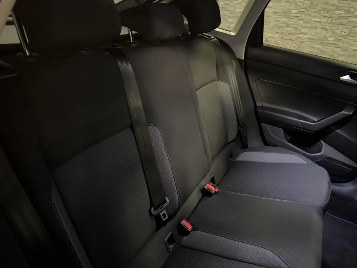 Vue intérieure de la banquette arrière en tissu gris foncé du Volkswagen Taigo 2024 côté droit avec ceintures de sécurité visibles.