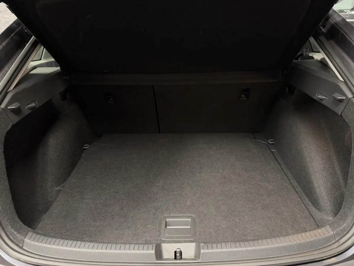 Coffre ouvert vu de l'arrière d'un Volkswagen Taigo gris, montrant un espace de chargement propre et spacieux.
