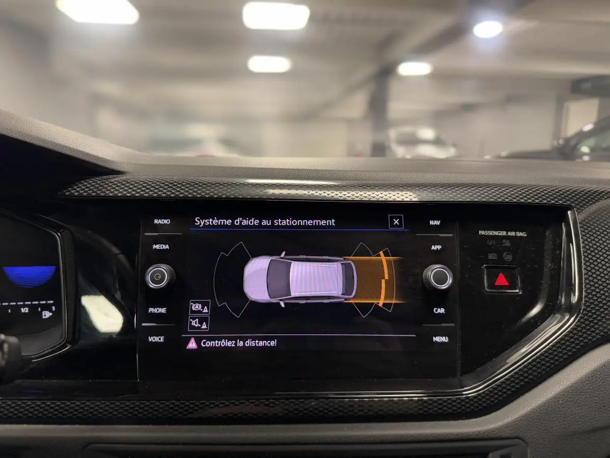 Vue rapprochée de l'écran tactile central du Volkswagen Taigo gris 2024 affichant l'aide au stationnement active.