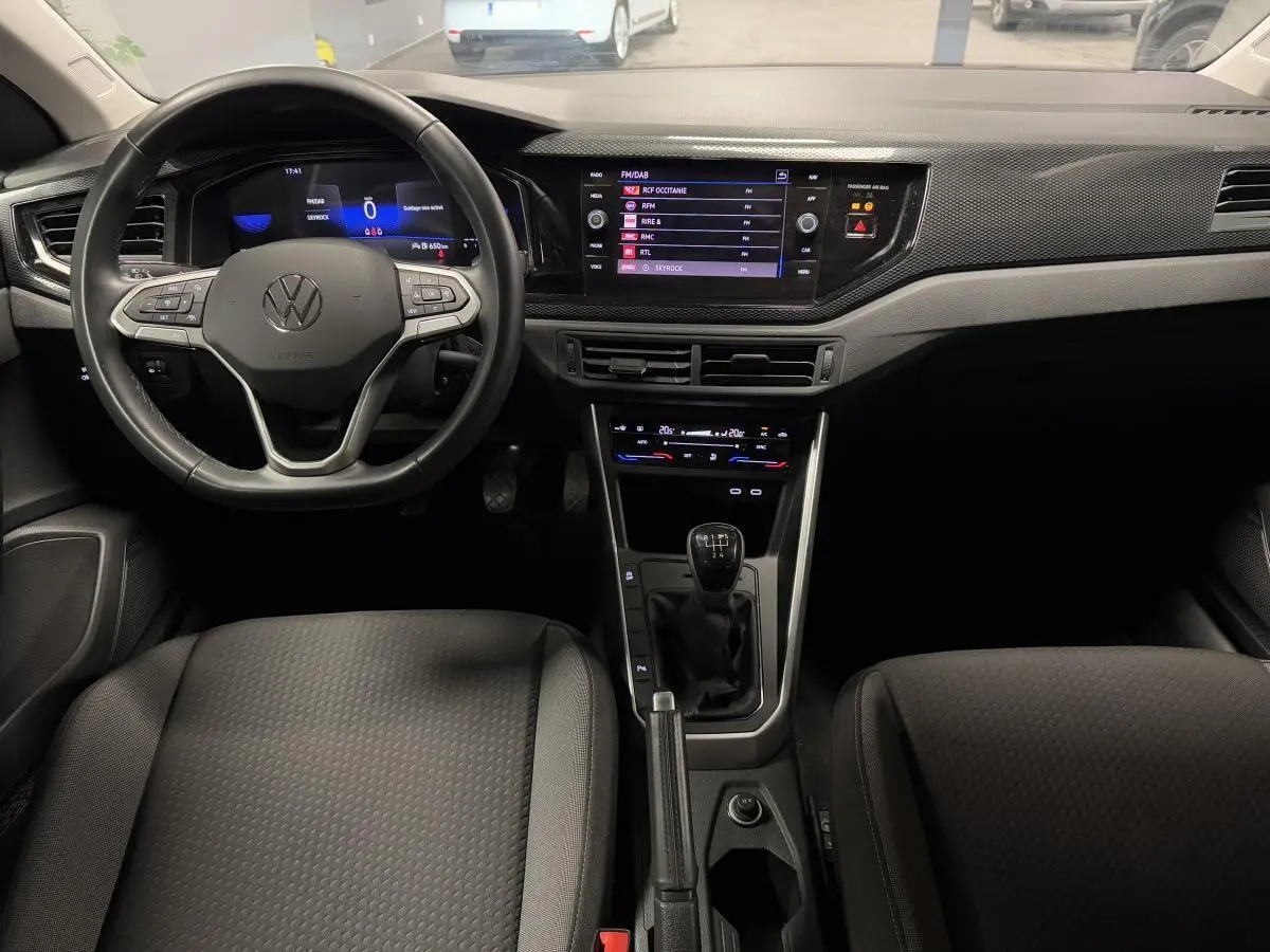 Vue intérieure avant du Volkswagen Taigo 1.0 TSI 95 Life 2024, tableau de bord avec écran tactile et levier de vitesse manuel.