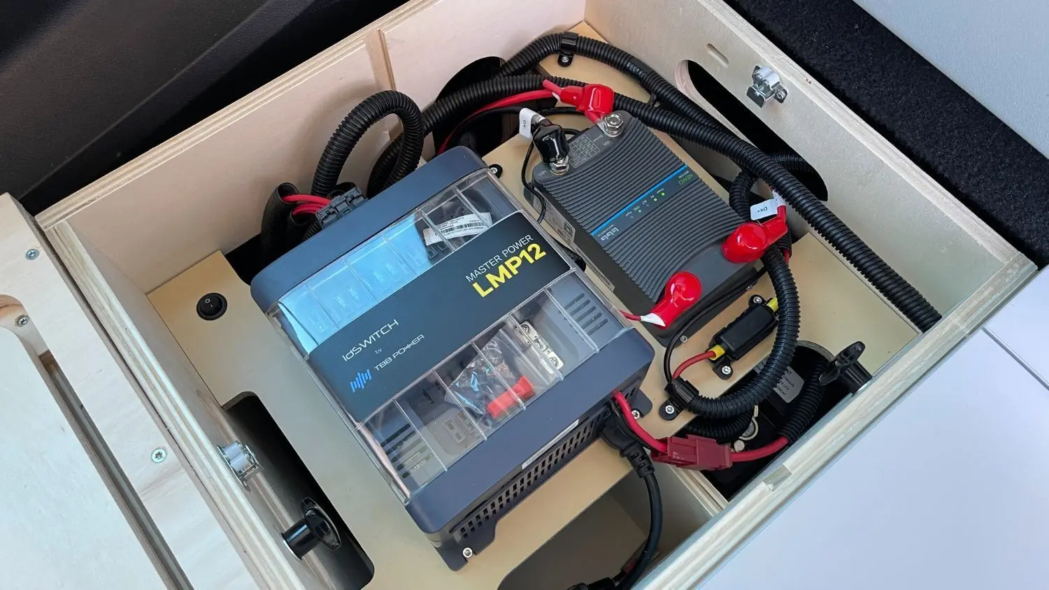 Vue rapprochée de la batterie auxiliaire AGM et du convertisseur électrique dans le coffre du Renault Trafic Fourgon gris comète.