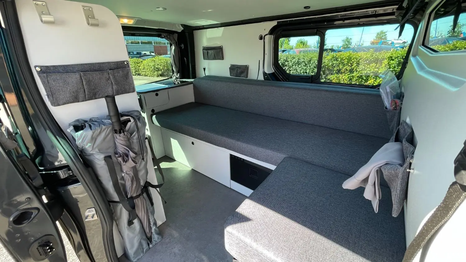 Intérieur du Renault Trafic gris comète vu côté droit, montrant banquette et rangements aménagés.