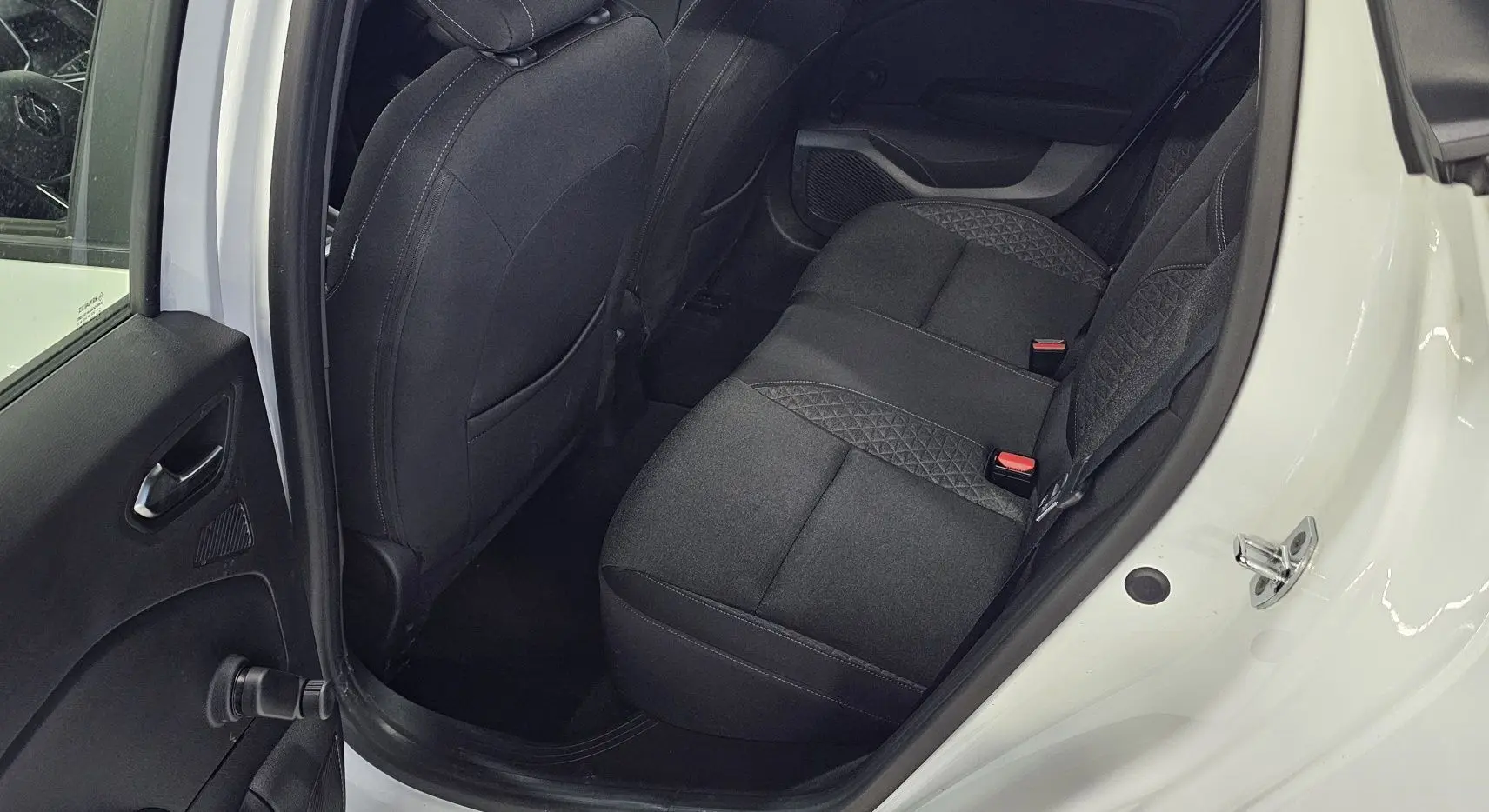 Vue côté gauche arrière de la Renault Clio blanche glacier 2020, montrant les sièges arrière en tissu gris noir.