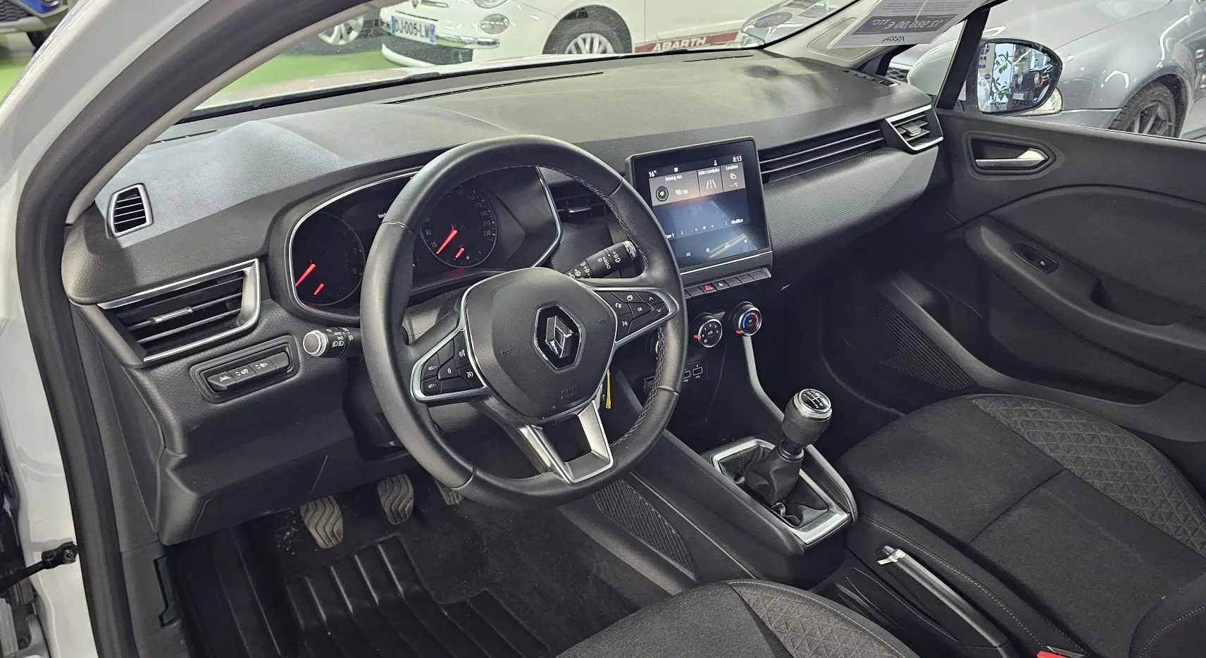 Intérieur avant droit de la Renault Clio 2020 blanc glacier, volant multifonction et boîte manuelle visibles.