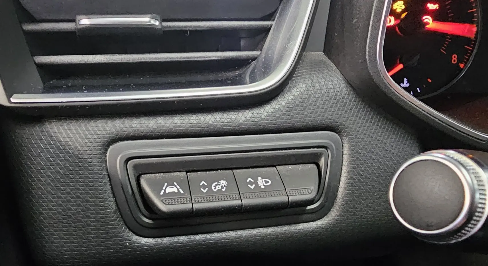 Gros plan sur les commandes d'assistance à la conduite dans l'habitacle noir texturé d'une Renault Clio blanche 2020.