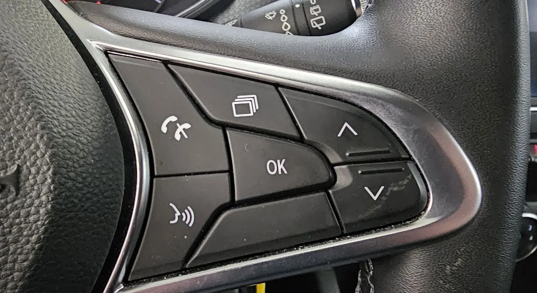 Gros plan sur les commandes multifonctions du volant noir de la Renault Clio blanche Glacier version Business 2020.