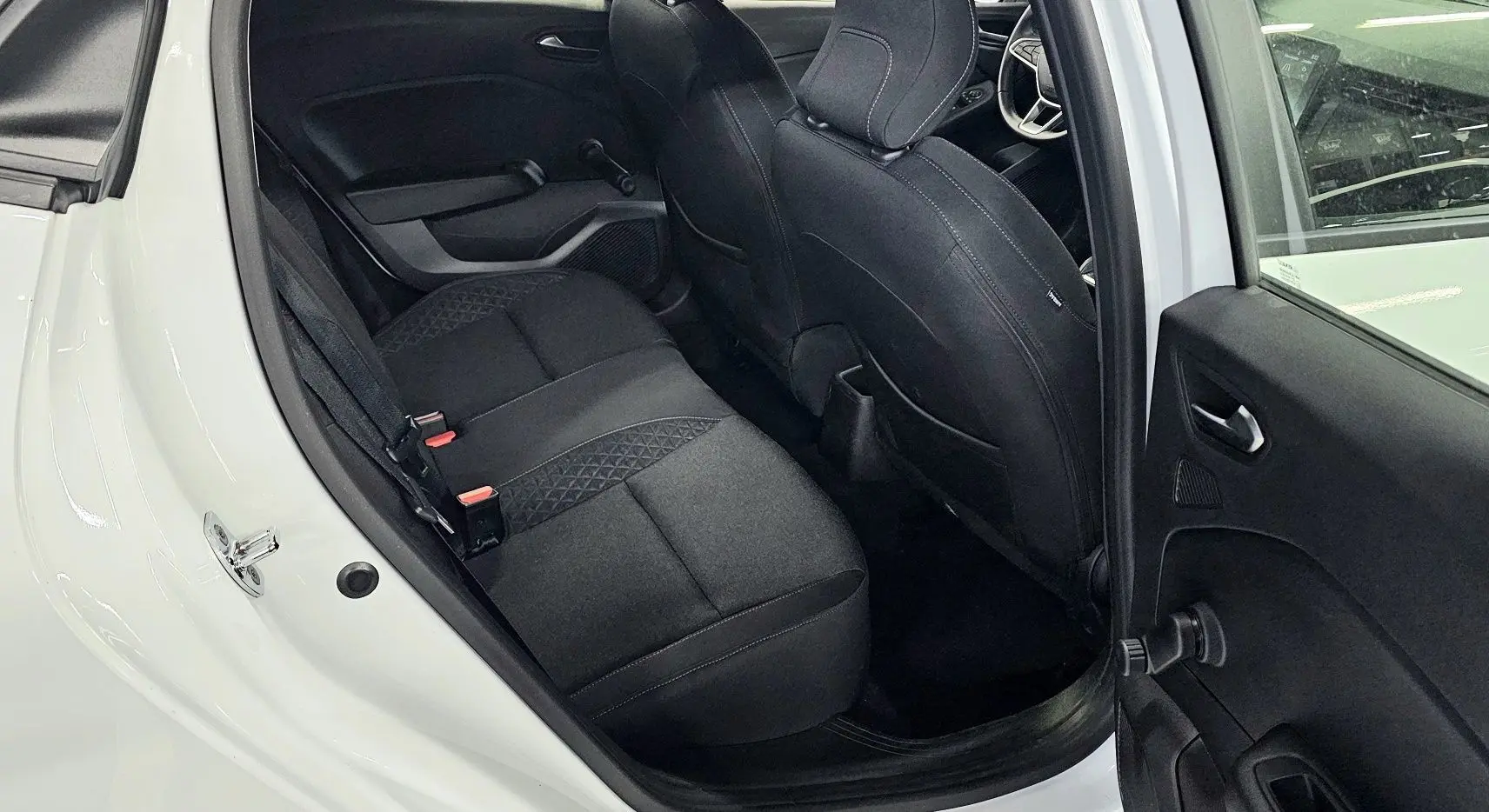 Vue intérieure côté gauche arrière d'une Renault Clio blanche glacier 2020, sièges tissu gris noir avec motifs géométriques.