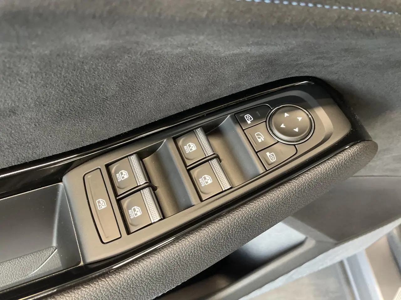 Gros plan sur les commandes des vitres électriques et rétroviseurs sur la portière côté conducteur du Renault Austral gris satin mat.