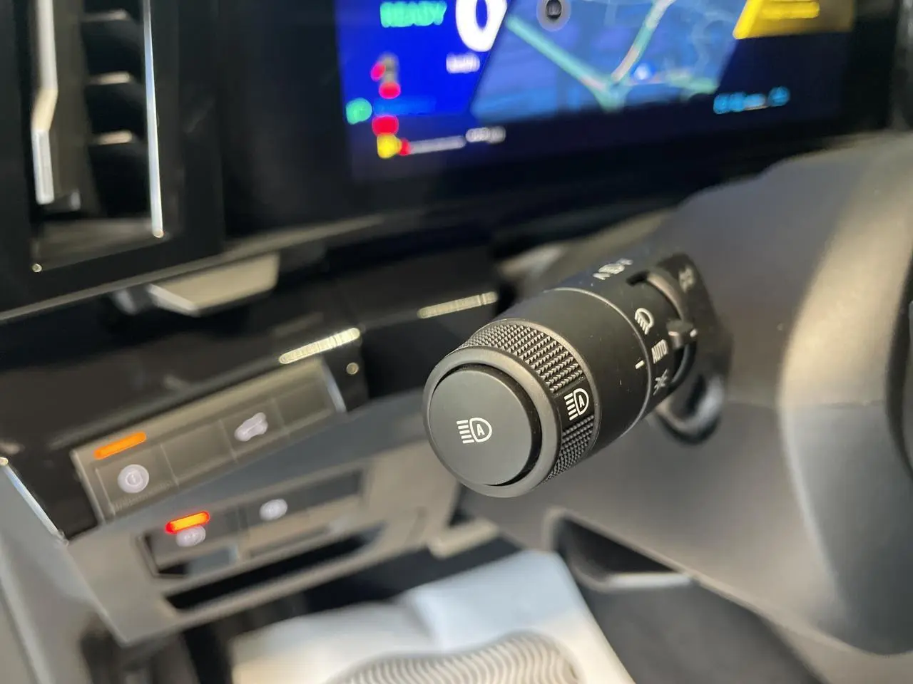 Gros plan sur la commande des feux automatiques du Renault Austral 2025, intérieur noir avec écran numérique.