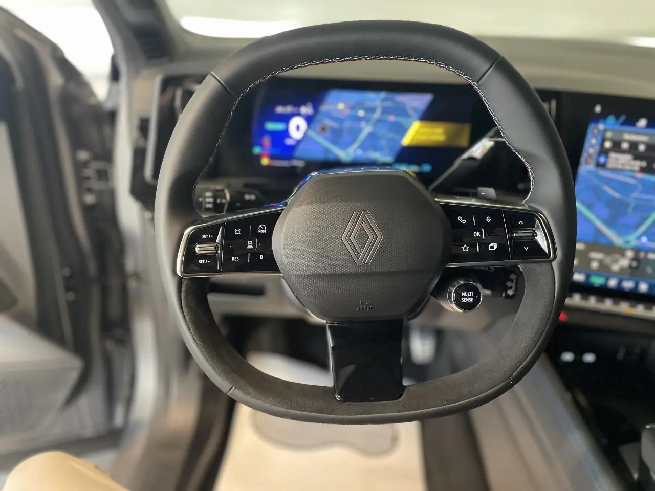 Volant Alcantara avec logo Renault au centre, vue frontale intérieure du tableau de bord numérique du Renault Austral 2025.