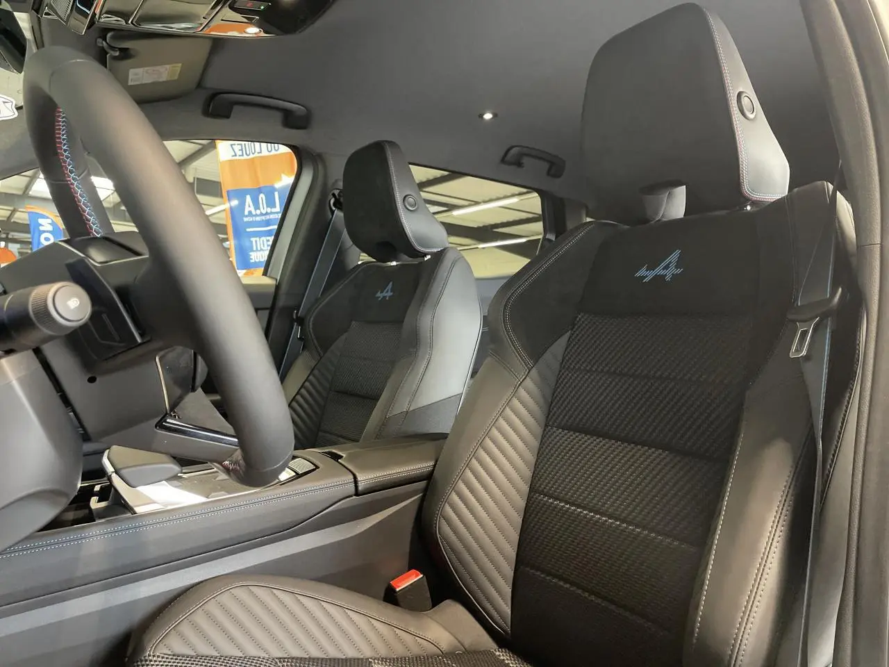 Vue intérieure côté conducteur du Renault Austral Esprit Alpine 2025, sièges en cuir noir avec logo Alpine bleu brodé.