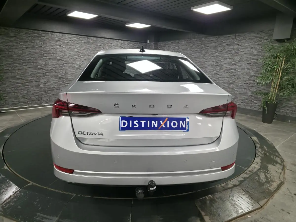 Vue arrière d'une Skoda Octavia gris métallisé avec attelage fixe et feux arrière LED dans un showroom.