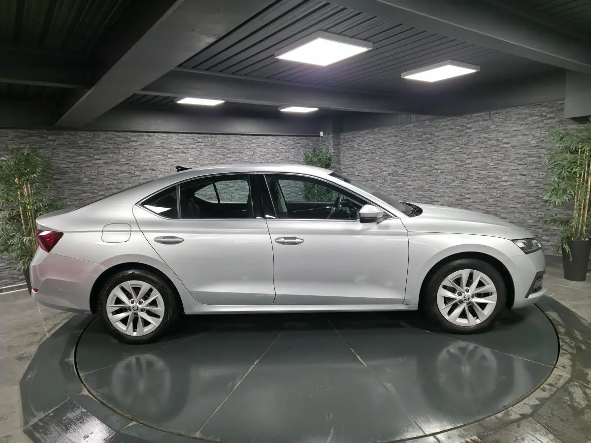 Vue latérale côté gauche d'une Skoda Octavia gris métallisé 2023 en intérieur avec jantes alliage 17 pouces.