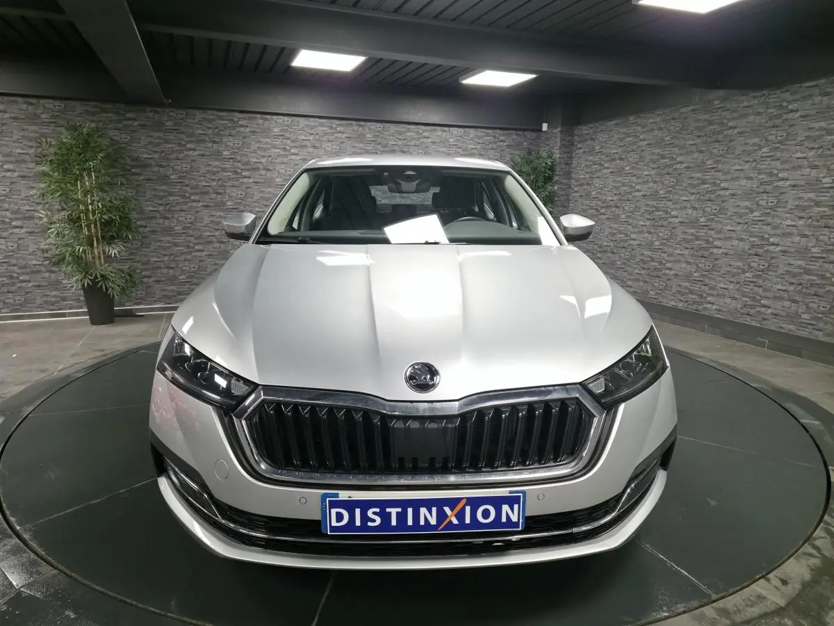 Vue avant d'une Skoda Octavia gris métallisé 2023 avec calandre noire et phares LED dans un showroom.