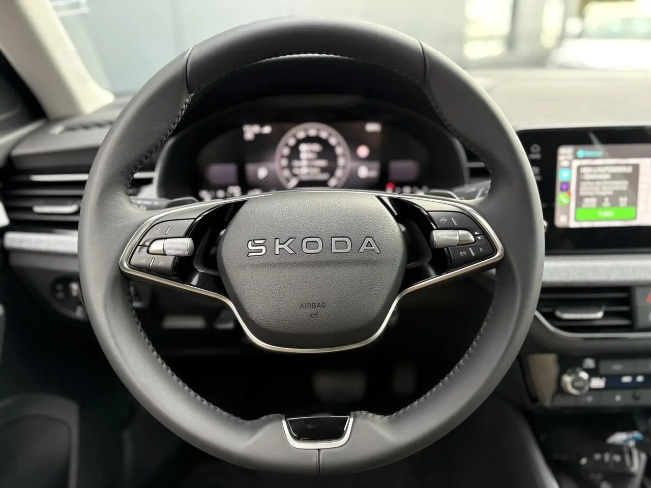Vue rapprochée du volant cuir noir multifonctions du Skoda Kamiq 2025 avec tableau de bord digital et écran tactile.