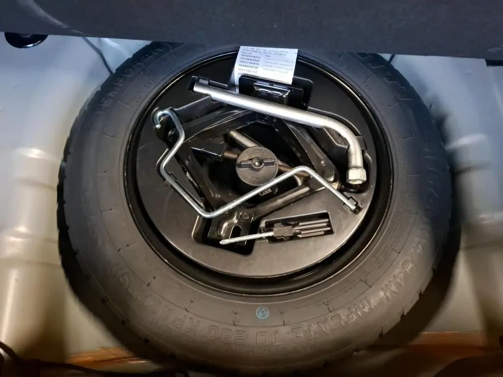 Gros plan sur la roue de secours et les outils de bord dans le coffre d'une FIAT 500 Gris Electroclash 2022.