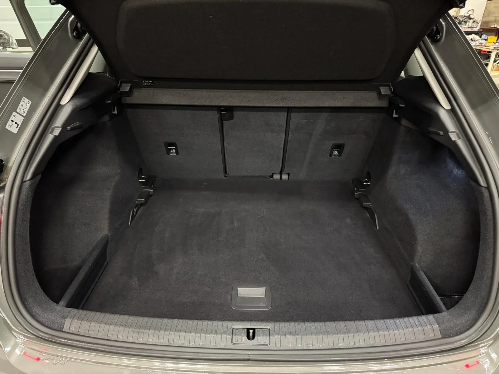 Coffre ouvert vu de l'arrière d'un Audi Q3 Business gris, montrant un espace de chargement propre et spacieux.