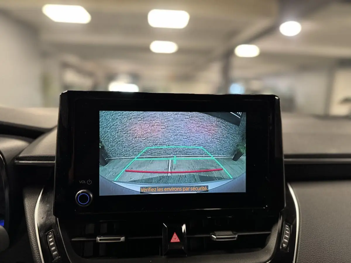 Écran central affichant la caméra de recul d'une Toyota Corolla hybride 2022, intérieur noir moderne.