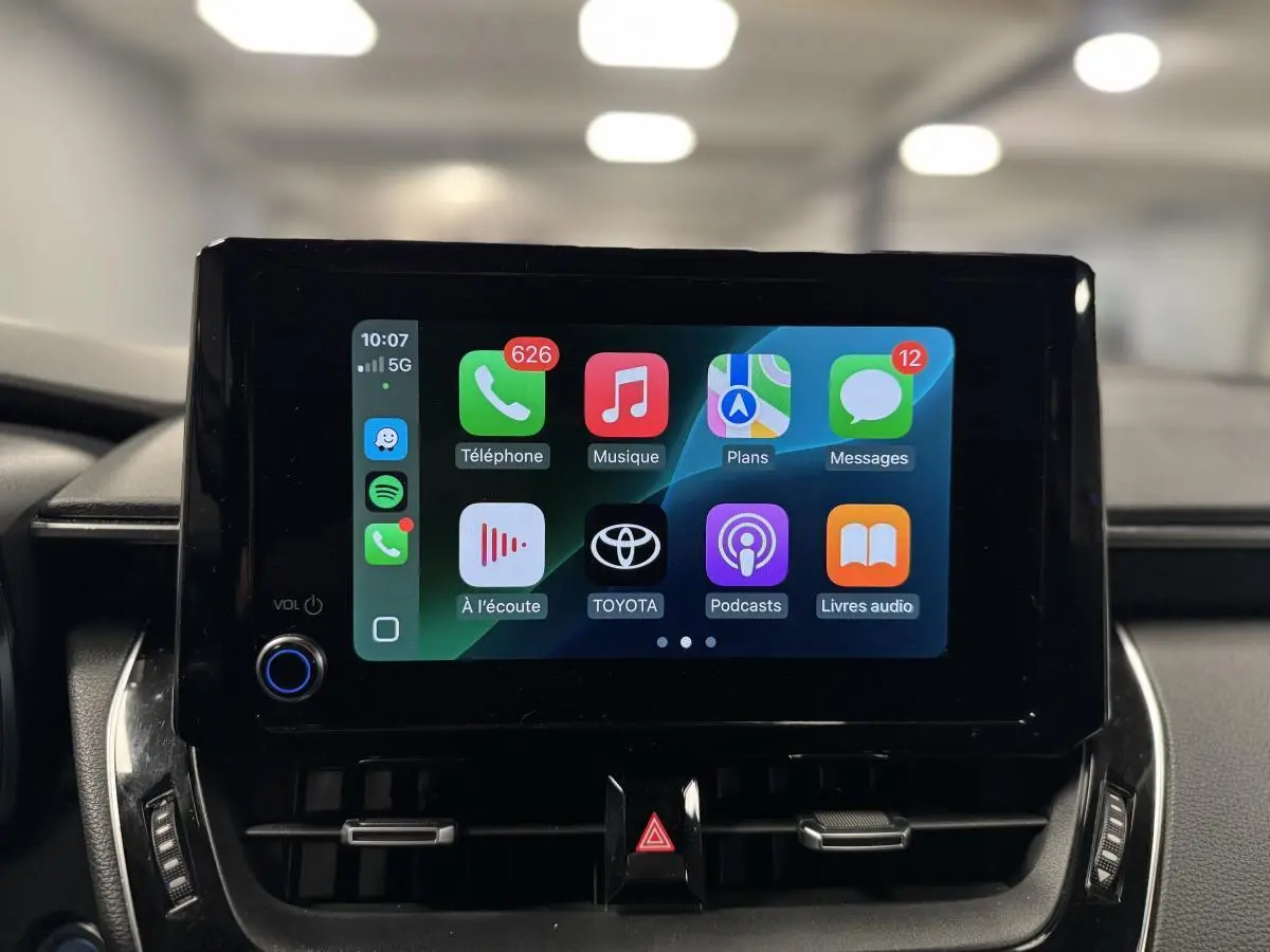 Écran tactile central de la Toyota Corolla hybride 2022 affichant Apple CarPlay dans un intérieur noir.