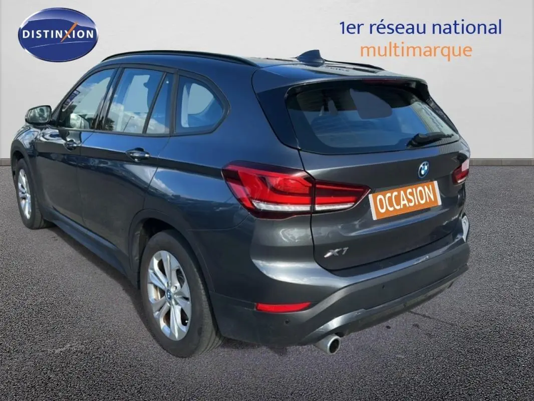 Vue 3/4 arrière droite d'un BMW X1 gris foncé avec jantes alliage et vitres surteintées, en extérieur sur sol bitumé.