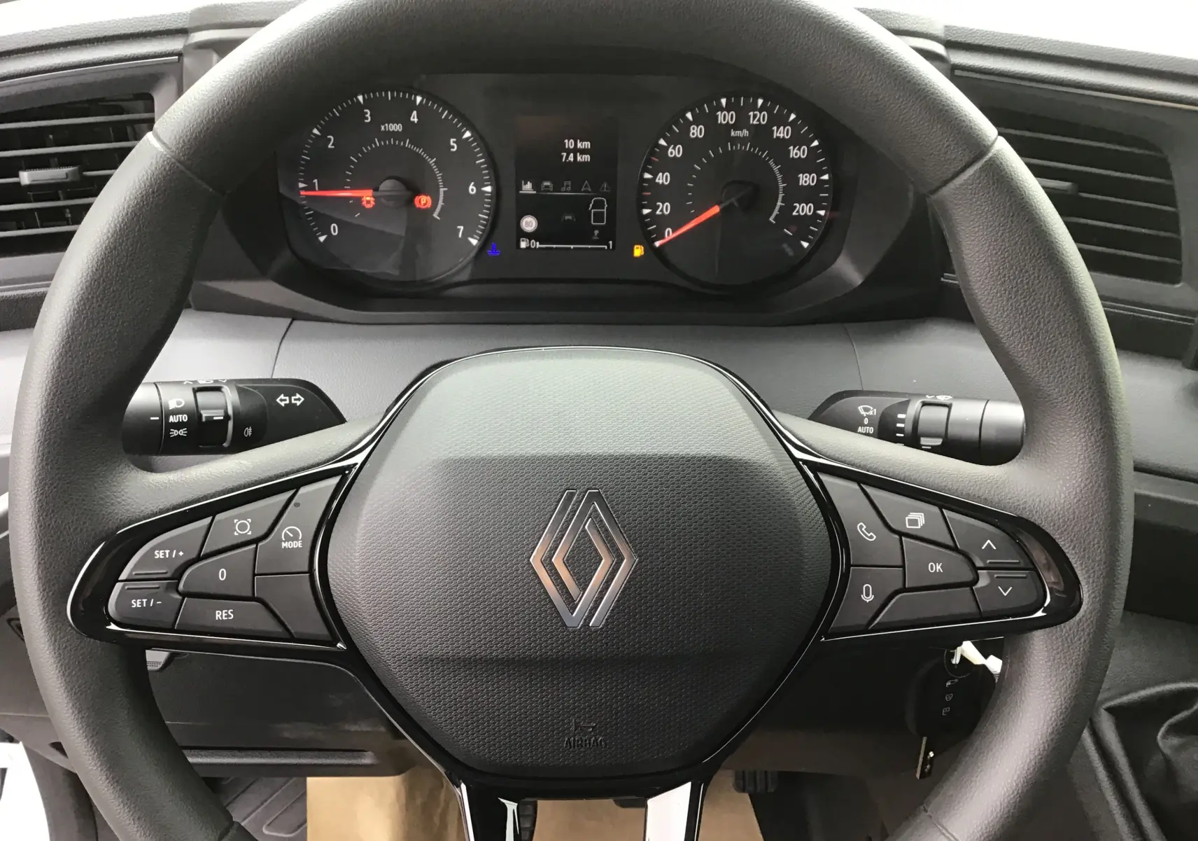 Vue rapprochée du volant noir de Renault Master blanc 2025 avec commandes intégrées et tableau de bord digital.