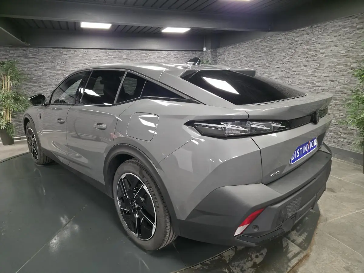 Vue 3/4 arrière droite d'une Peugeot 408 gris métallisé avec jantes alliage noires et feux arrière LED griffés.