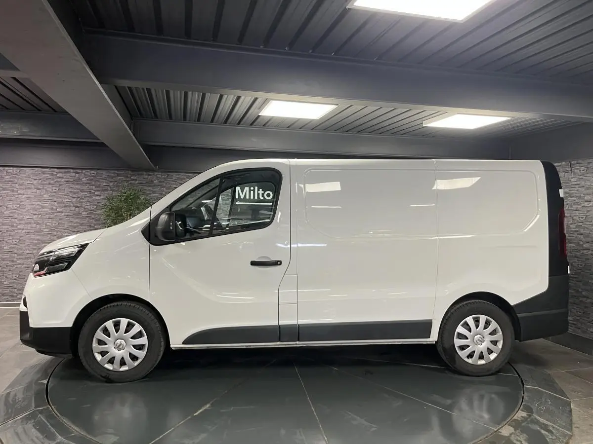 Profil côté gauche du fourgon blanc Nissan Primastar N-Connecta 2022 avec enjoliveurs de roues et protections noires.
