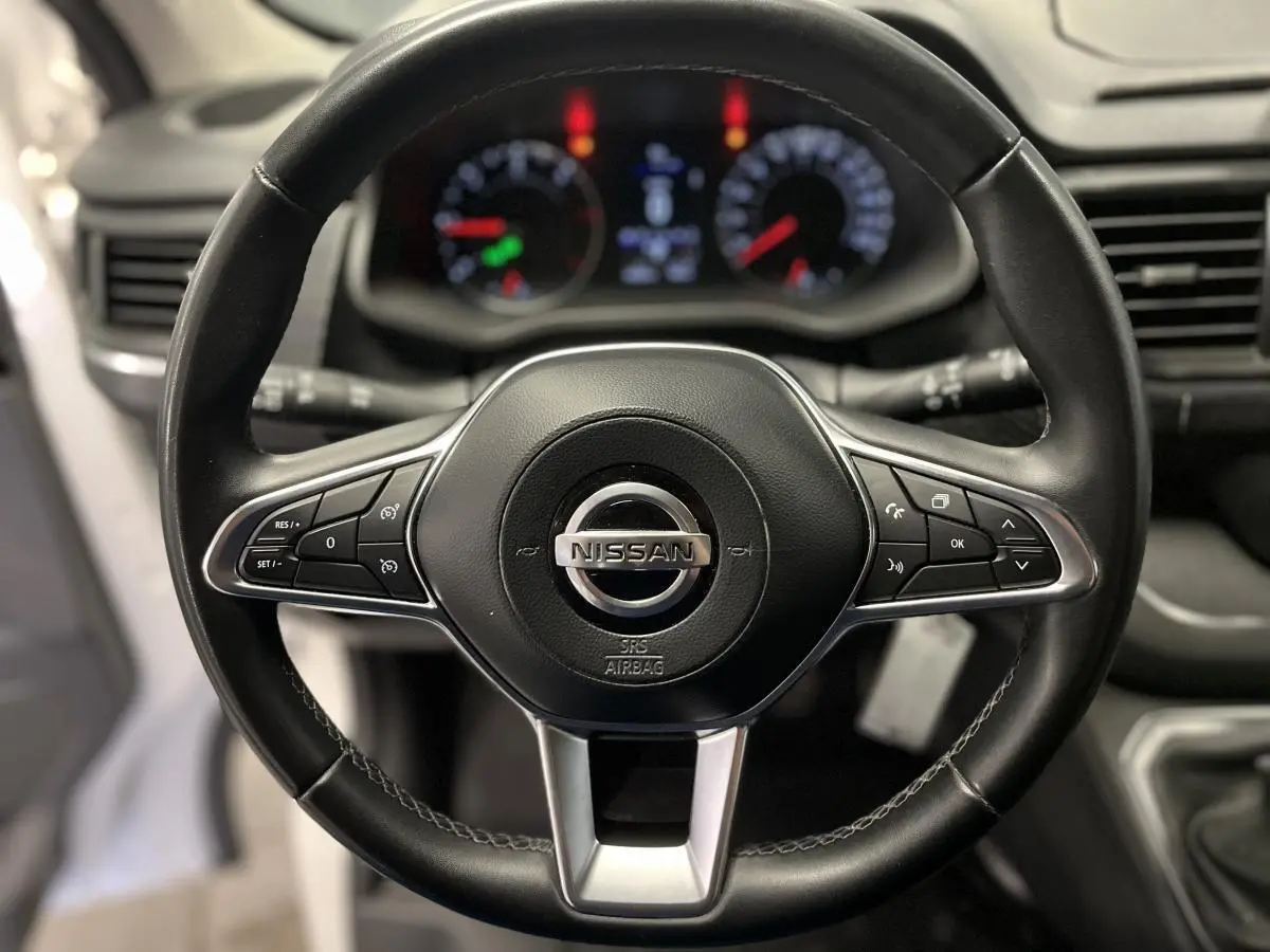 Vue rapprochée du volant en cuir noir du Nissan Primastar 2022 avec commandes intégrées et tableau de bord flou en arrière-plan