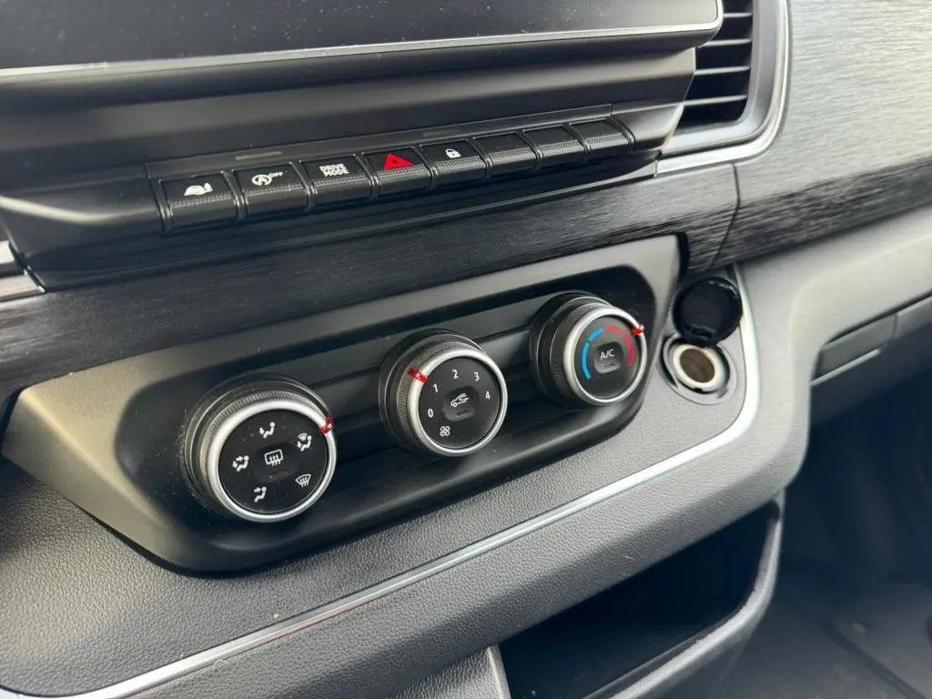 Gros plan sur les commandes de climatisation et ventilation du tableau de bord noir du Nissan Primastar blanc 2022.