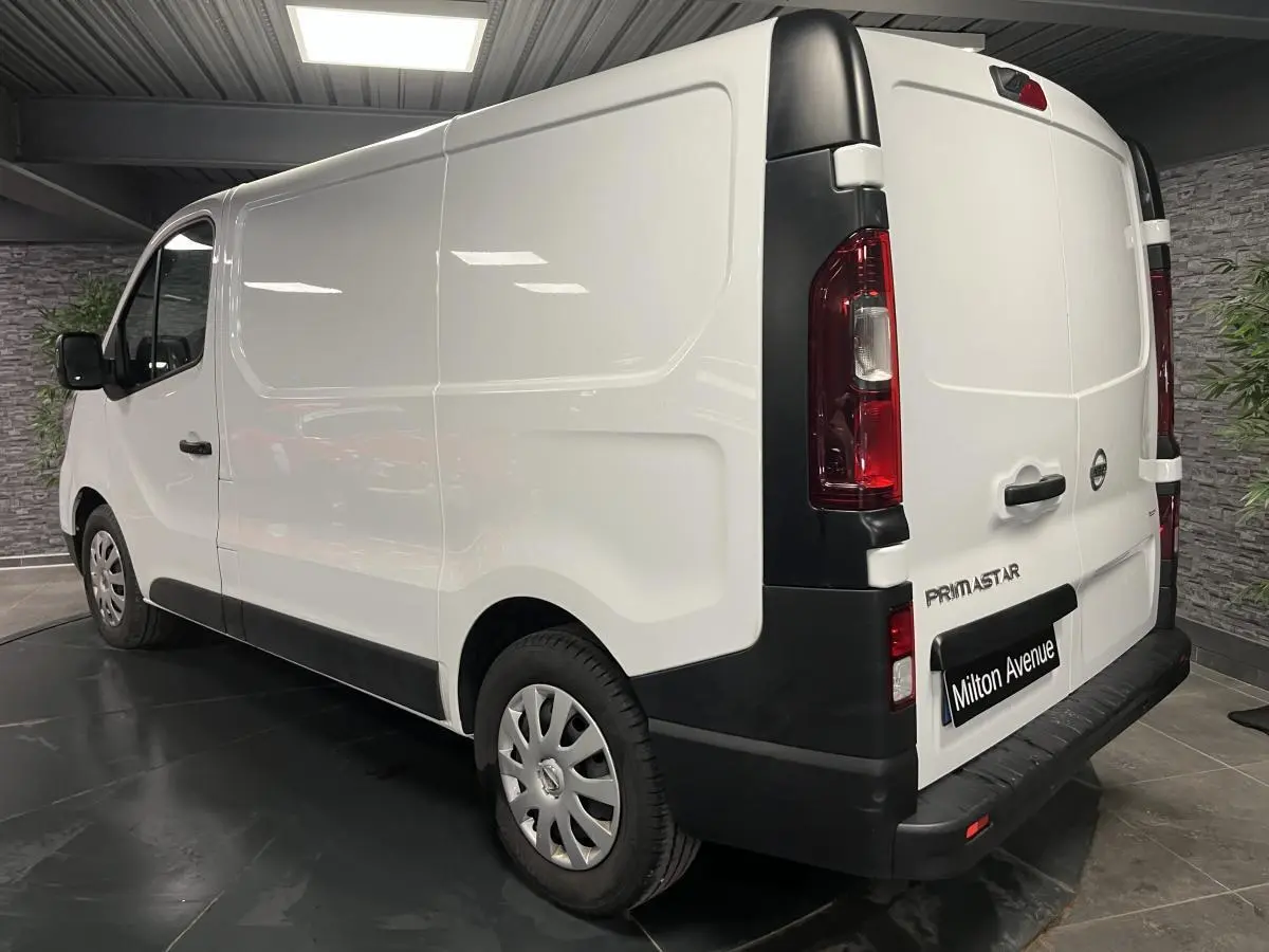 Vue 3/4 arrière droite d’un utilitaire Nissan Primastar blanc avec protections noires et jantes acier 16 pouces.