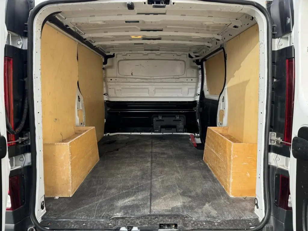 Vue arrière intérieure du fourgon blanc Nissan Primastar 2022 avec plancher et protections latérales en bois.