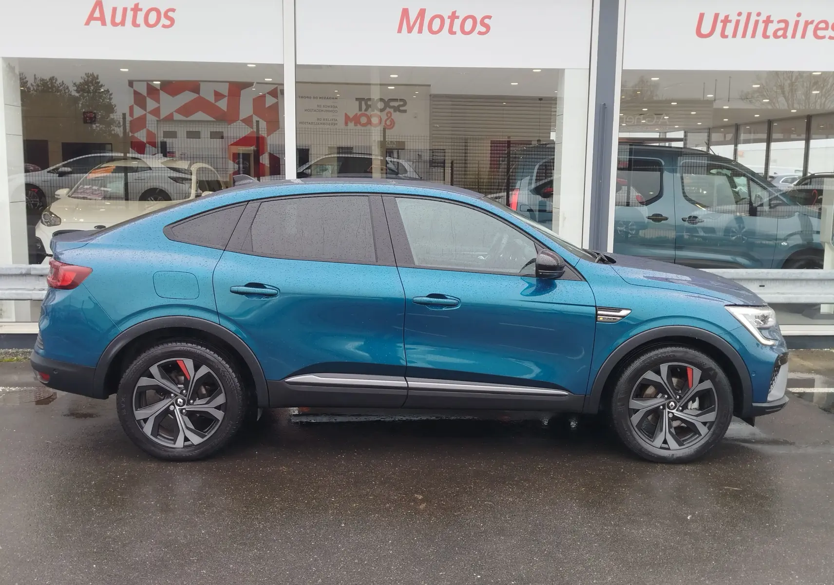 Vue de profil côté gauche d'un Renault Arkana bleu Zanzibar 2022 avec jantes noires et détails rouges sur les étriers.