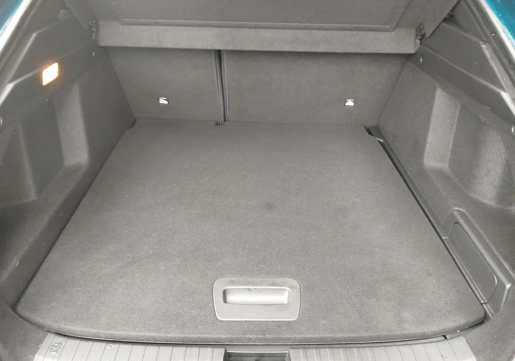 Coffre spacieux vu de l'arrière d'un Renault Arkana 1.6 E-Tech bleu Zanzibar, avec plancher plat et éclairage intérieur.