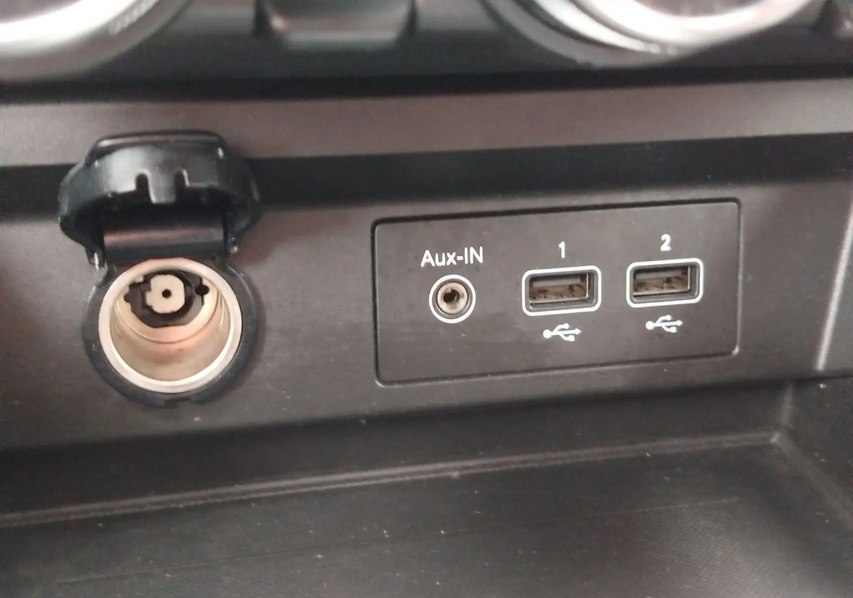 Détail intérieur du Renault Arkana 2022 montrant une prise allume-cigare ouverte, une entrée Aux-IN et deux ports USB.