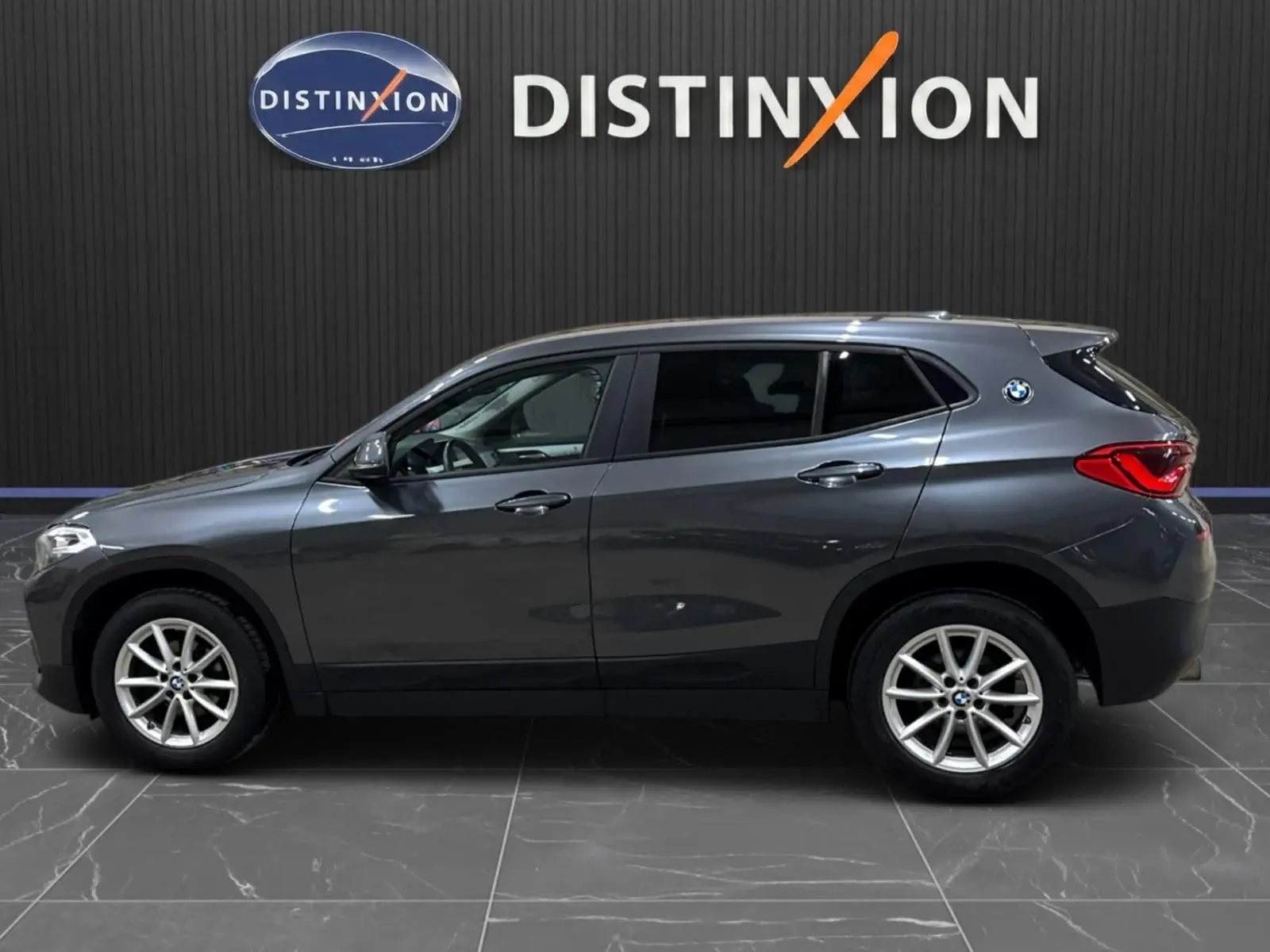 BMW X2 gris minéral métallisé vue de profil côté gauche, vitres arrière surteintées et jantes alliage visibles.