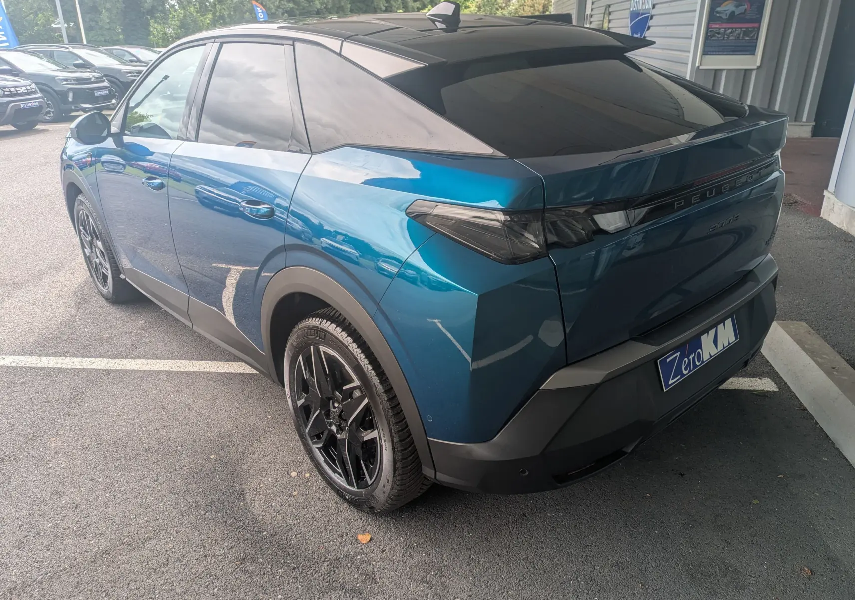Vue 3/4 arrière droite du Peugeot 3008 Hybrid bleu Obsession avec toit noir et jantes noires.