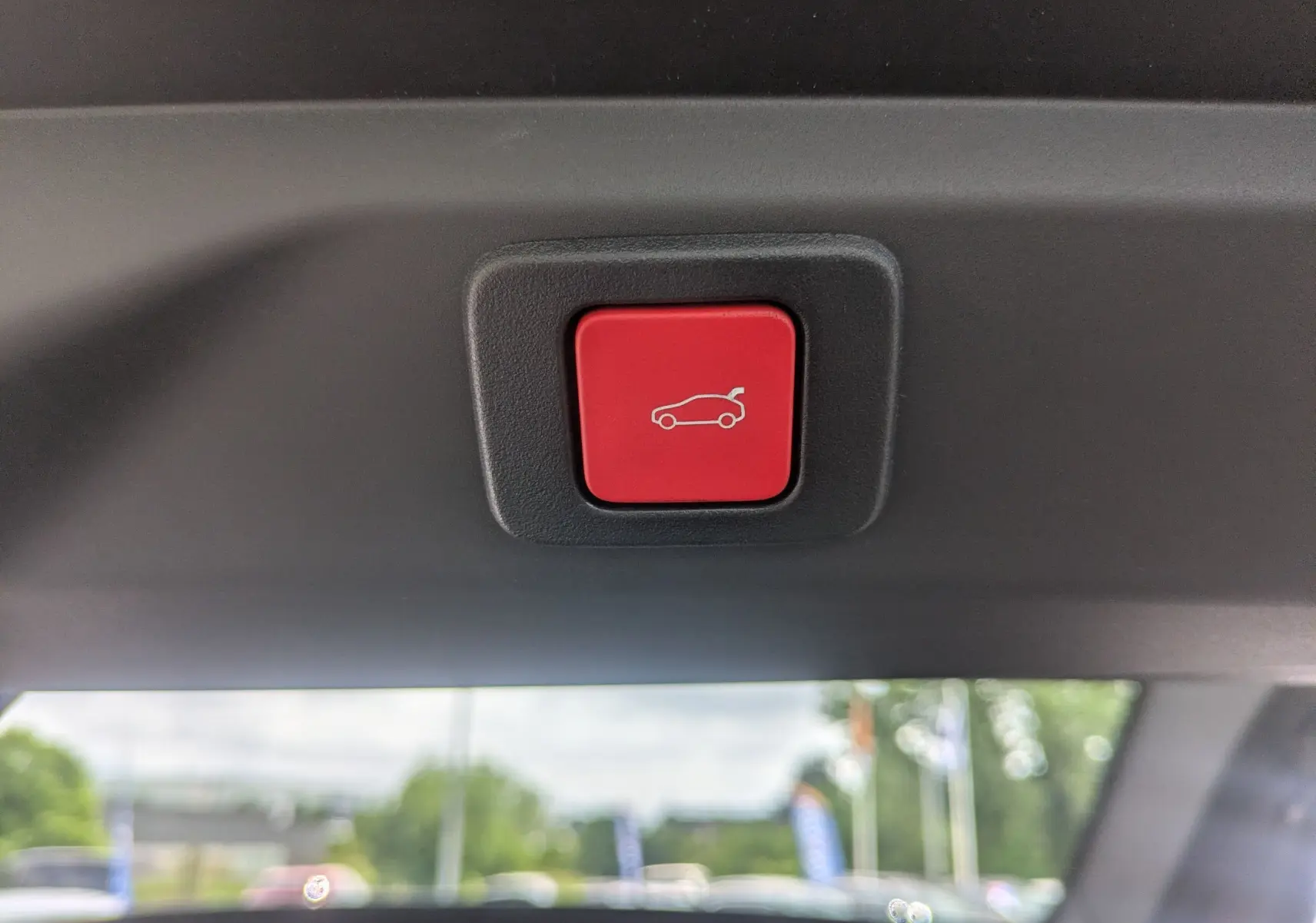 Bouton rouge d'ouverture électrique du hayon visible depuis l'intérieur arrière du Peugeot 3008 Hybrid 2026.