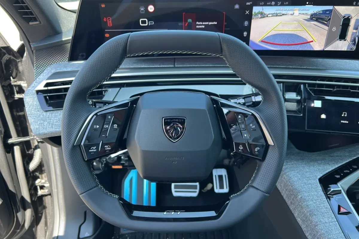 Vue rapprochée du volant cuir multifonctions GT de la Peugeot 3008 Hybrid 145, avec tableau de bord digital et caméra 360° affichée.