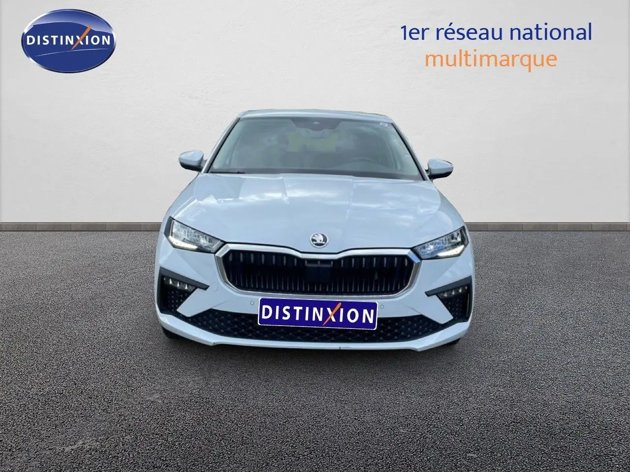 Vue frontale d'une Skoda Scala blanc glacier 2025 avec calandre noire et phares LED allumés.