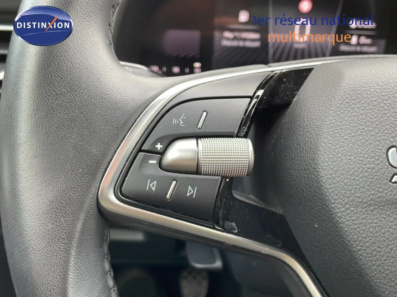 Gros plan sur les commandes du volant côté gauche d’un Skoda Scala blanc glacier, mettant en valeur la molette et les boutons multifonctions.