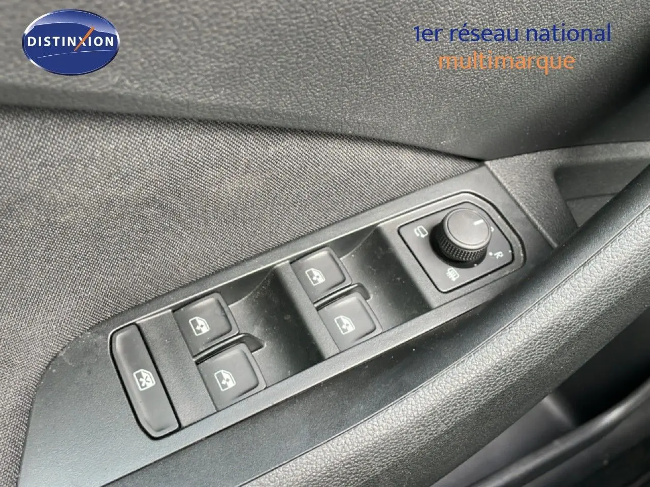 Gros plan sur les commandes des vitres électriques et réglage des rétroviseurs côté conducteur d’une Skoda Scala blanc glacier.