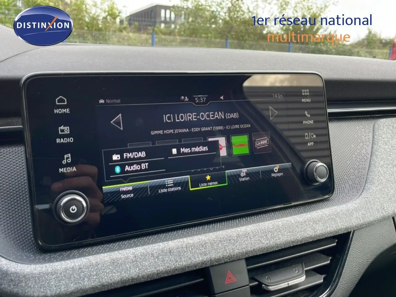 Écran tactile central de la Skoda Scala blanc glacier 2025, affichant les options radio et médias dans l’habitacle.