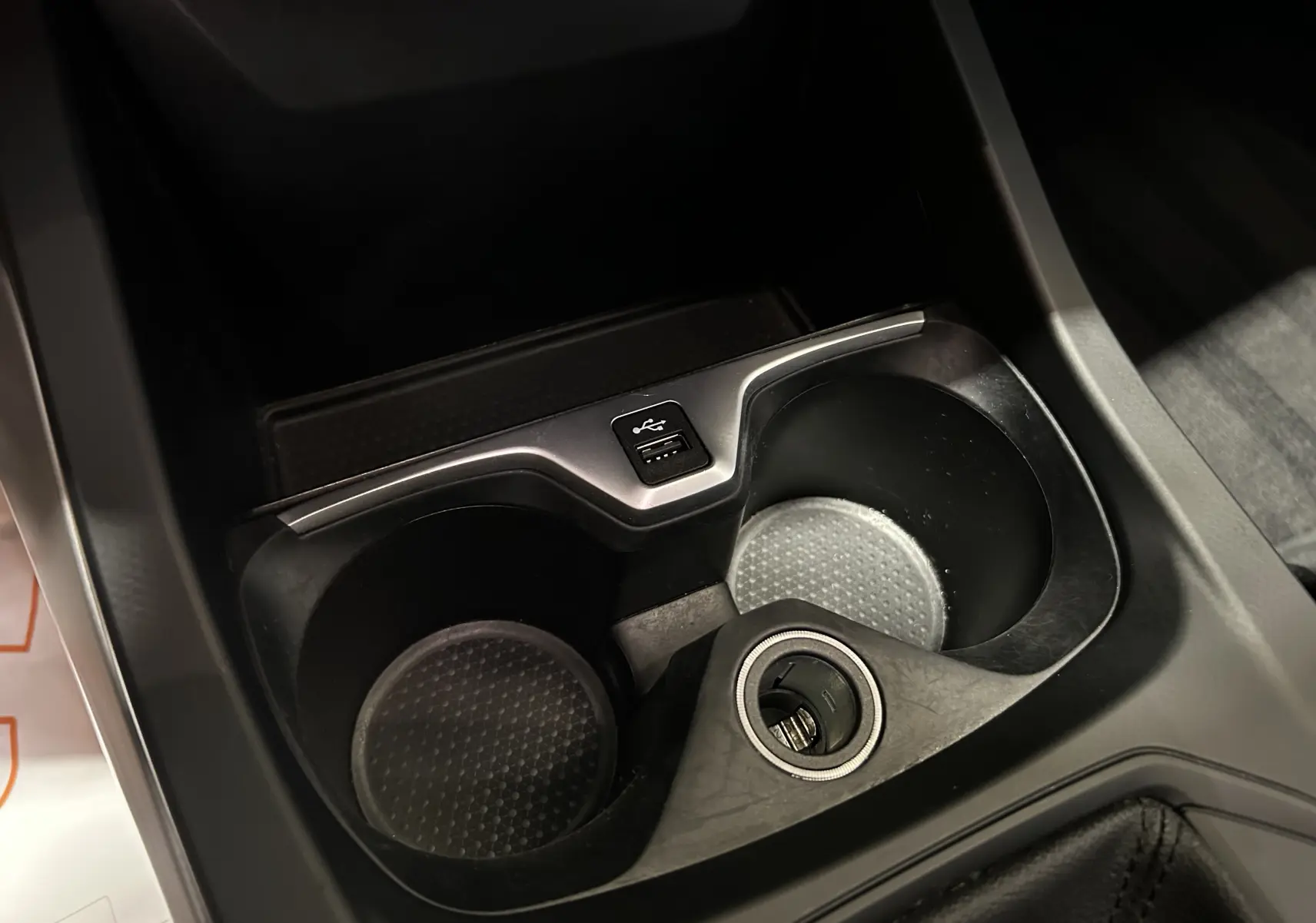 Gros plan sur les porte-gobelets et prise USB du console centrale d'une BMW Série 1 noire de 2023.